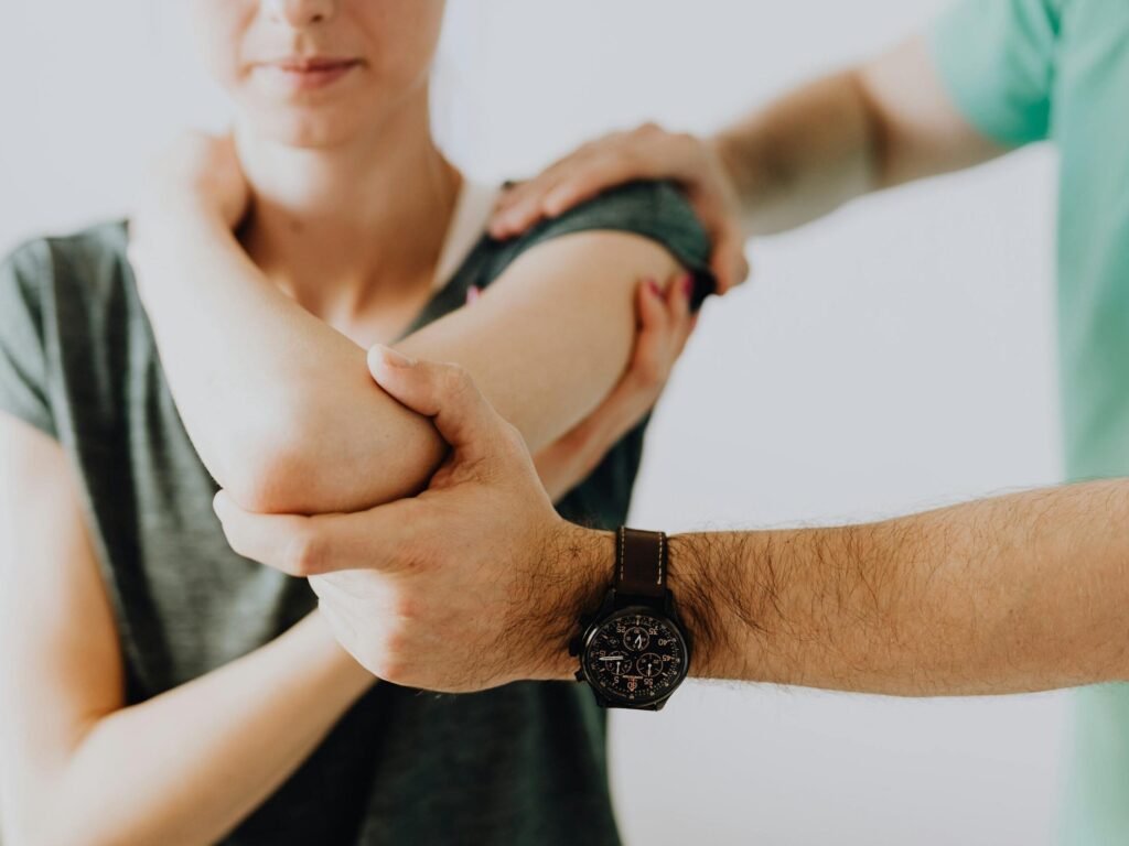 A chiropractor adjusting a patient's arm in a clinic setting, focusing on health and care.