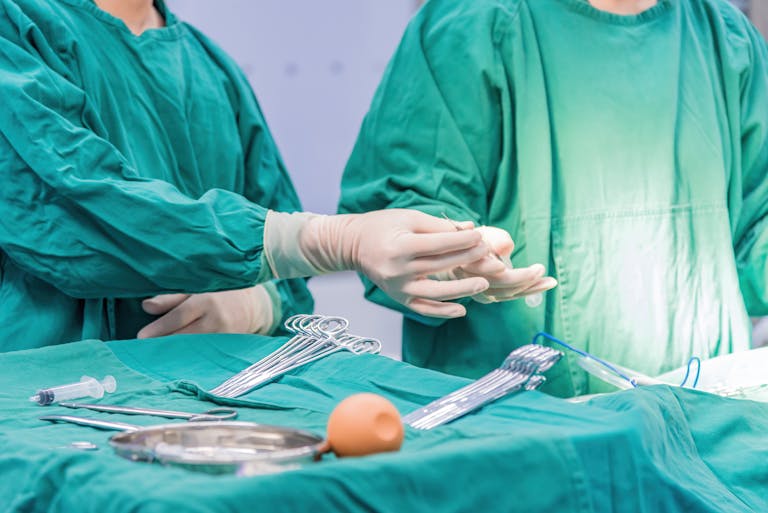 Medical professionals in gowns perform a surgical operation in a hospital setting.